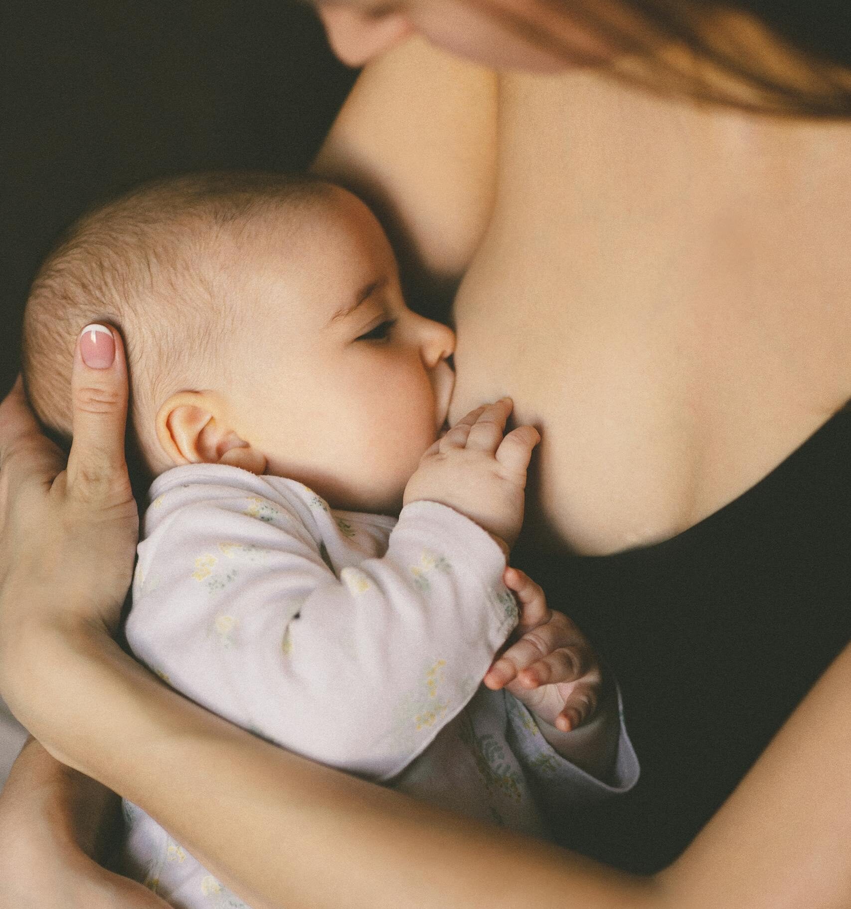 A close-up of a mother lovingly breastfeeding her baby, symbolizing care and motherhood.