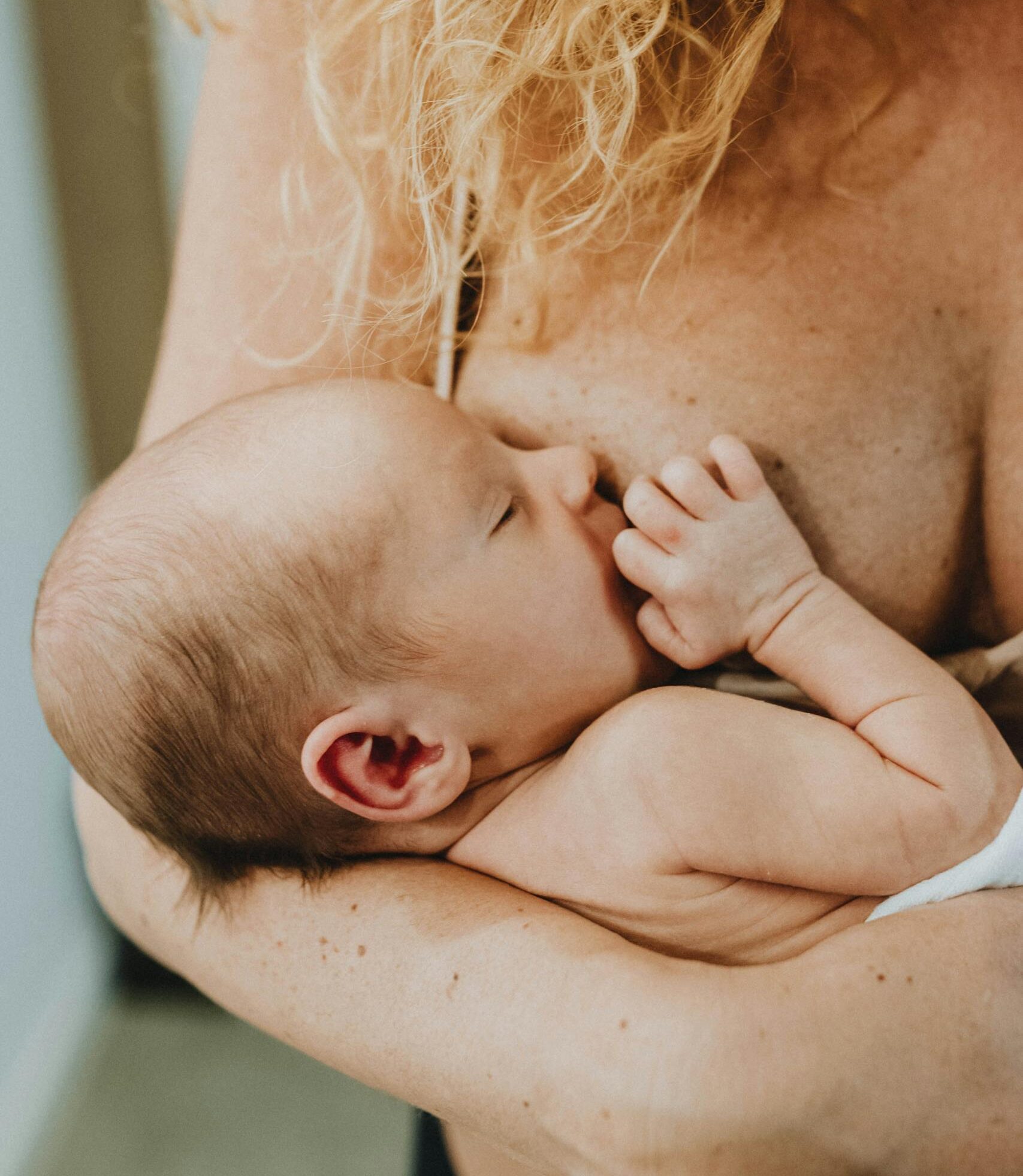 Tender moment of a mother breastfeeding her newborn baby in a cozy indoor setting.