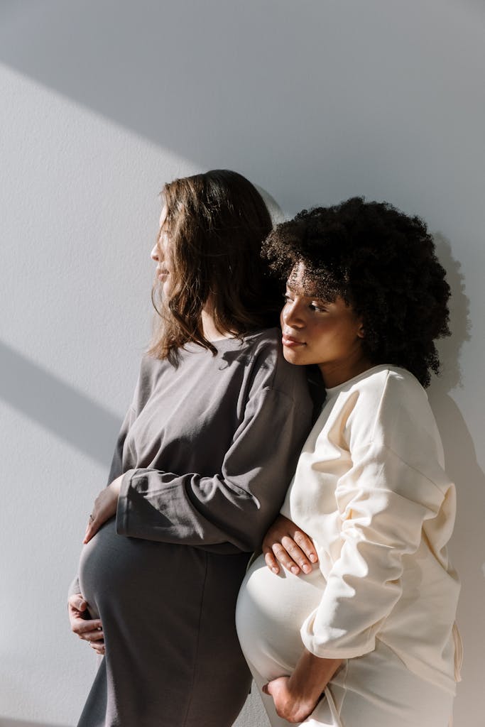 Two pregnant women embracing each other, celebrating diverse motherhood and unity.